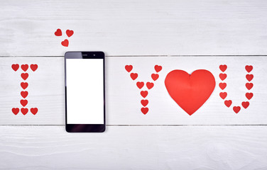 Top view of mobile smart phone with white blank screen and sign I love you from paper hearts on wooden background, copy space. Flat lay. Valentines day application mockup