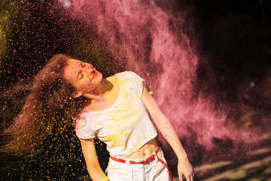 Expressive brunette model having fun in a cloud of pink powder at Holi festival