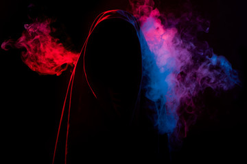 mysterious dark silhouette hidden by colorful smoke on black background