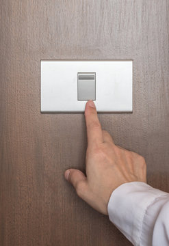 Energy saving concept with business woman's hand turn off switch light button on wood panel