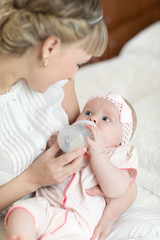 Mom holding and giving milk formula to baby from bottle