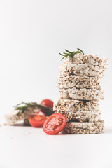 stack of rice cakes with rosemary and tomatoes on white tabletop