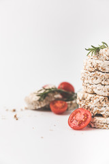 Fototapeta na wymiar close-up shot of stack of rice cakes with rosemary and tomatoes on white tabletop