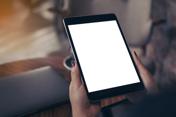 Mockup image of woman's hands holding black tablet pc with blank white desktop screen in cafe