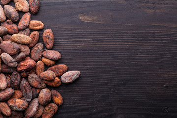Raw cocoa beans on dark wood