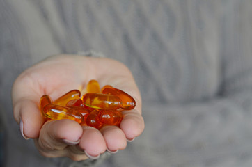 Woman's hands holding omega 3 fish oil capsules over knitted sweater background