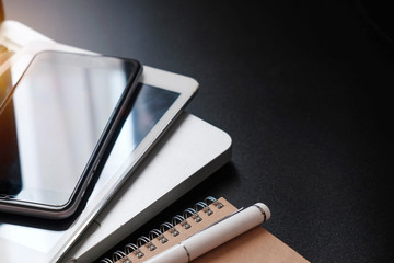 Black office desk table with a lot of things tablet, laptop ,smartphone ,notepad and coffee cup notepad. Top view with copy space.
