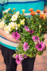 Seniorin steht mit einem Strauß Ringelblumen in der Hand, Blumenstrauß