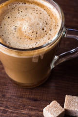 Coffee with milk in a glass mug on a wooden table