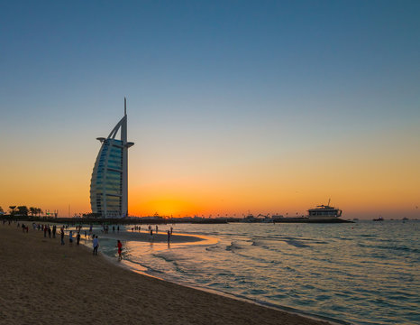 People waiting for new year celebration at the beach in last day of the year. The world's first seven stars luxury hotel Burj Al Arab and Dubai Marina in background 