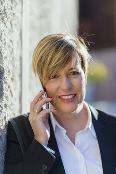 Executive talking on phone looking at camera on the street