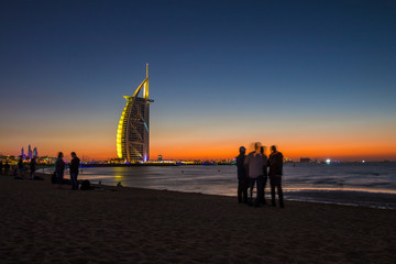 People waiting for new year celebration at the beach in last day of the year. The world's first seven stars luxury hotel Burj Al Arab and Dubai Marina in background 
