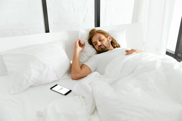 Wake Up. Man Sleeping In Bed With Phone Alarm