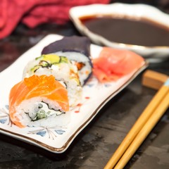 Tasty sushi rolls on a plate with sauce and ginger