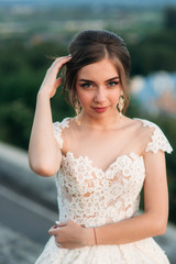 Naklejka premium Young girl in wedding dress on city background at sunset. Summer