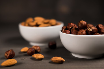 Two white cups filled with nuts, almonds and hazelnuts
