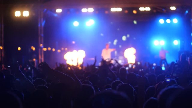 Excited people waving hands up in air, enjoying music at concert