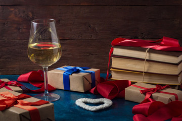 Valentine's Day. Glass of Wine, Packed Gifts, Ribbon, Books, Heart on a Blue Background