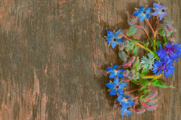 Abstract background with blue bouquet of garden flowers on a dark wooden table vintage, top view.