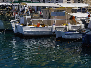Fototapeta na wymiar Fishing boats moored at Greek island port. Day view of traditional small boats anchored at port of Thassos island capital Limenas .