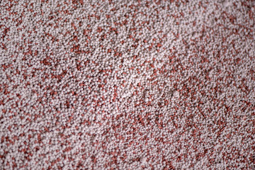 Shot of mixed chemical, artificial nitrogen plant fertilizer granules in factory. Big heaps of mineral pellets creating abstract textures, patterns. Minerals used in agriculture, farms, fields 