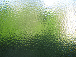 Water drops on green transparent glass close up