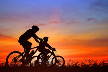 Obraz na płótnie Canvas Silhouette man and bike relaxing on blurry sunrise background