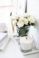 White interior decor with new hand-made candle and bouquet of fr