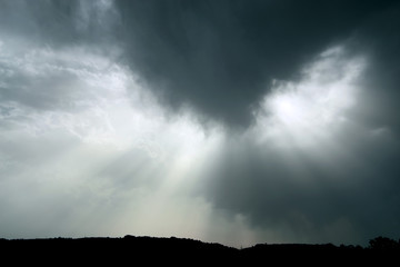 Rays of sun behind clouds of gray color
 