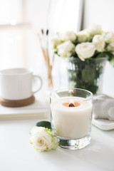 White room interior decor with burning hand-made candle and bouq
