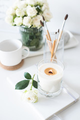 White room interior decor with burning hand-made candle and bouq