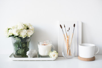 White room interior decor with burning hand-made candle and bouq