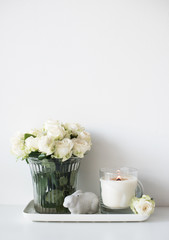 White room interior decor with burning hand-made candle and bouq