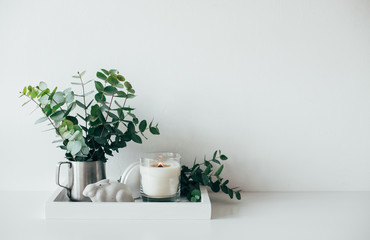 Natural eco home decor with green leaves and burning candle on t - obrazy, fototapety, plakaty