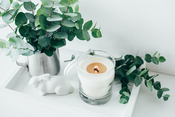 Natural eco home decor with green leaves and burning candle on t