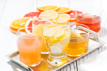 assortment of fresh citrus juices in glasses on white table, closeup