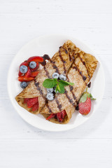 crepes with berries and chocolate sauce, top view vertical