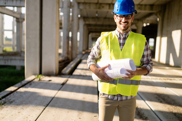 Architect holding rolled up blueprints at construction site