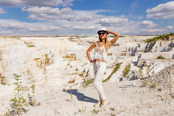 young woman in white suit and hat in full length, marble quarry, white marble