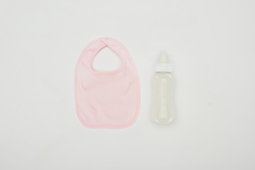 top view of baby bib and bottle of milk isolated on white