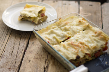 Homemade vegetarian lasagna with a white plate on a side