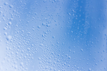 Naklejka na ściany i meble Blue wet glass rain drops on surface blue sky