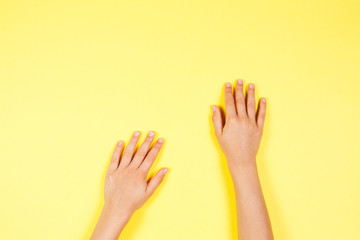two children hands on yellow background
