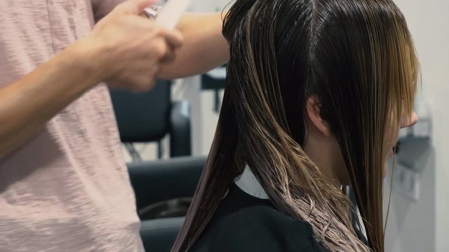 male hairdresser hold in hand between fingers lock of hair, comb and scissors closeup. Trim the tips of the hair by scissors. stages of hair salon haircuts. wash hair before the haircut.