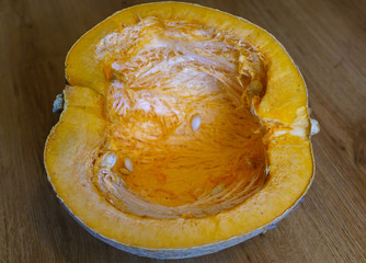 Half of the cut orange gourd, with selected seeds.