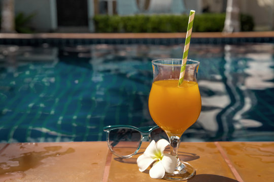 Orange juice with sunglasses on swimming pool