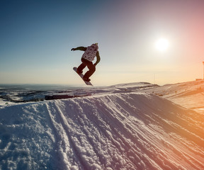 Jumping snowboarder in mountains