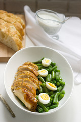 Roasted chicken breasts served with fried egg and boiled green beans.