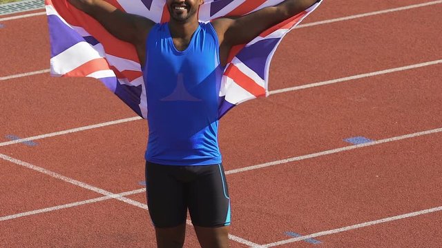 Muscular member of British sports team triumphantly holding flag over his head