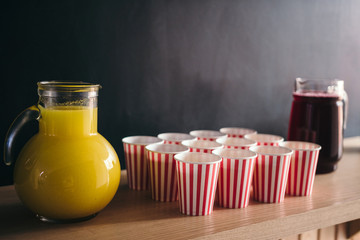 Juice of glass jars with red paper cups against blackboard with space for text.